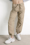 Pantalón jogger beige de mujer con cintura elástica y zapatillas blancas