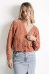 Mujer con cárdigan de punto color terracota y falda de mezclilla clara, moda femenina casual.