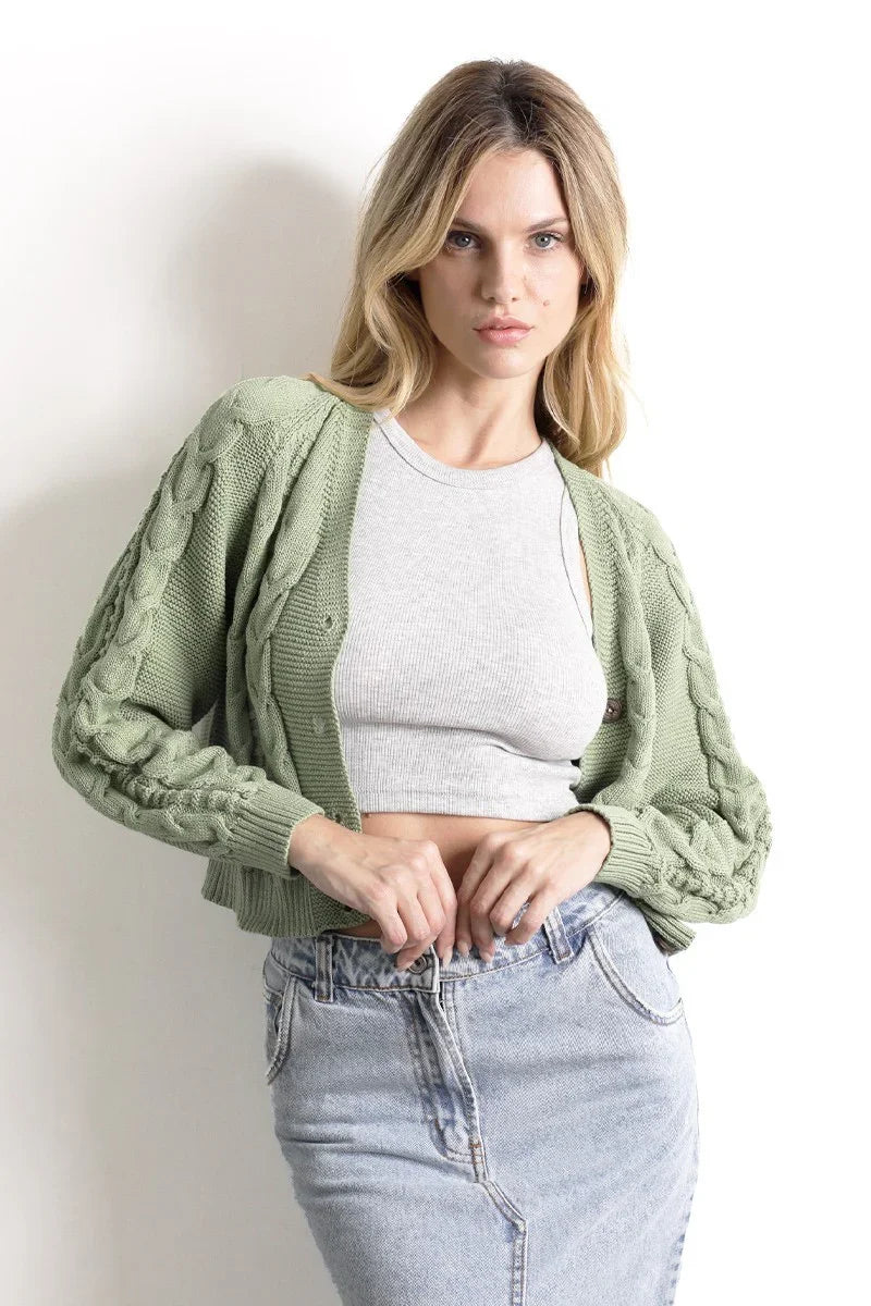 Mujer con cárdigan verde de punto, top corto gris y falda de mezclilla clara.